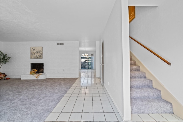 interior space with brick wall, light colored carpet, a notable chandelier, and a fireplace