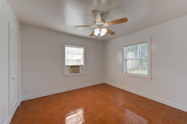 empty room with cooling unit, a wealth of natural light, ceiling fan, and parquet flooring