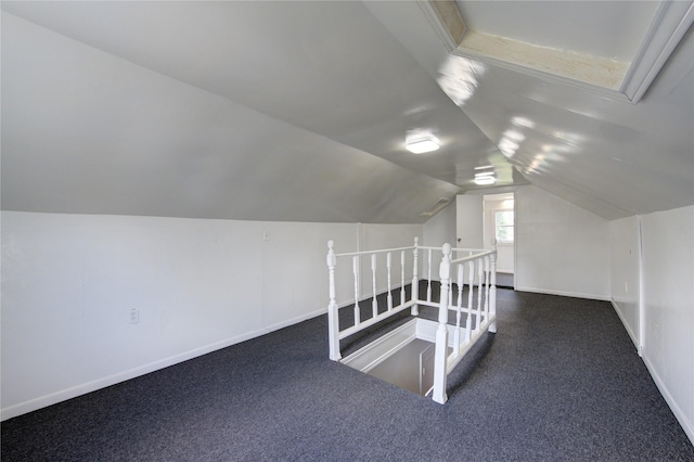 additional living space featuring lofted ceiling and dark colored carpet