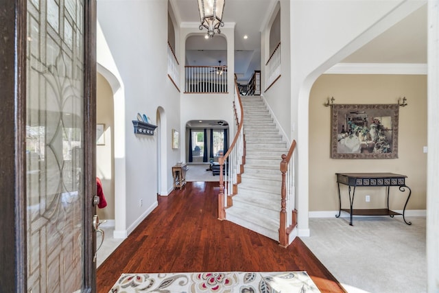 entrance foyer with dark wood-type flooring, ornamental molding, and a high ceiling