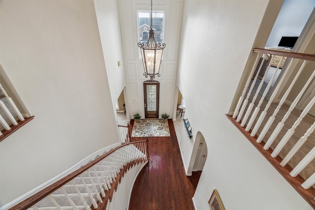 stairs with hardwood / wood-style flooring, a towering ceiling, and a notable chandelier