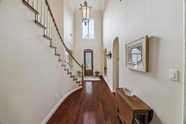 foyer entrance featuring ornamental molding, wood-type flooring, and a towering ceiling