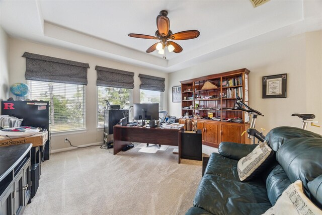 office featuring light colored carpet, a raised ceiling, and ceiling fan