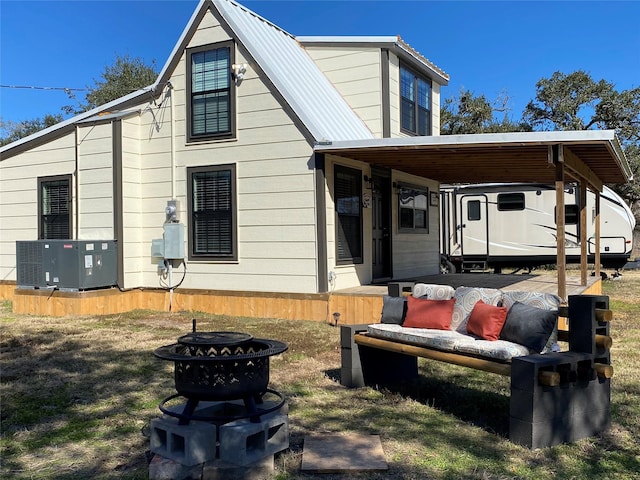 rear view of property featuring a fire pit and central air condition unit