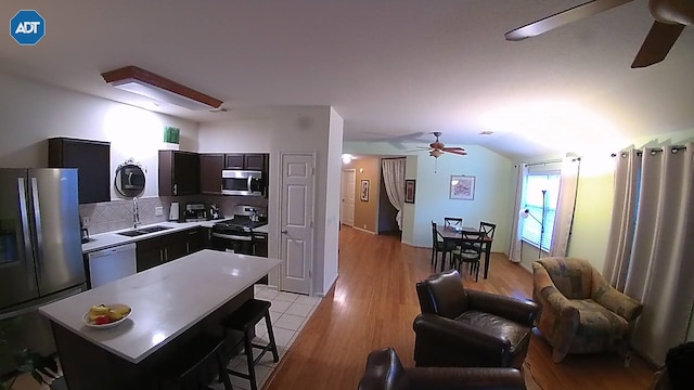 kitchen featuring tasteful backsplash, a center island, vaulted ceiling, appliances with stainless steel finishes, and ceiling fan