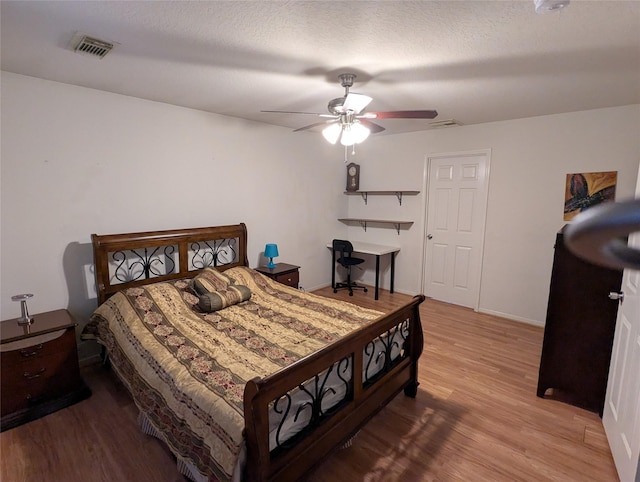 bedroom with ceiling fan, a textured ceiling, and light hardwood / wood-style flooring