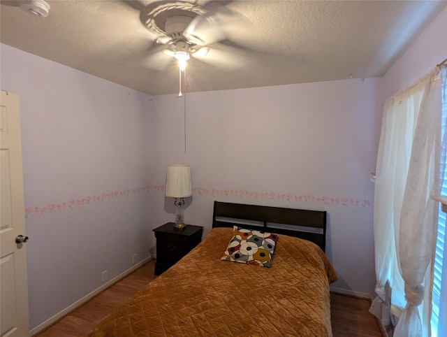 bedroom featuring ceiling fan, hardwood / wood-style flooring, and a textured ceiling