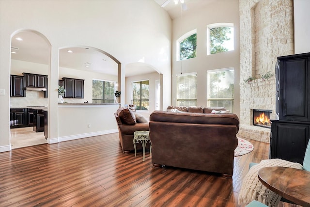 living room featuring a fireplace, dark hardwood / wood-style flooring, and a high ceiling