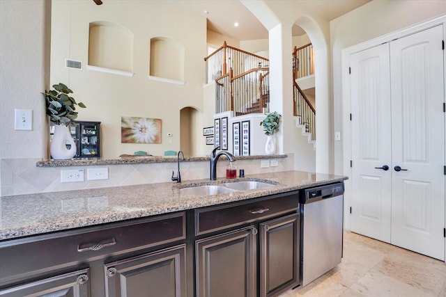 kitchen with dishwasher, sink, a high ceiling, dark brown cabinetry, and light stone counters