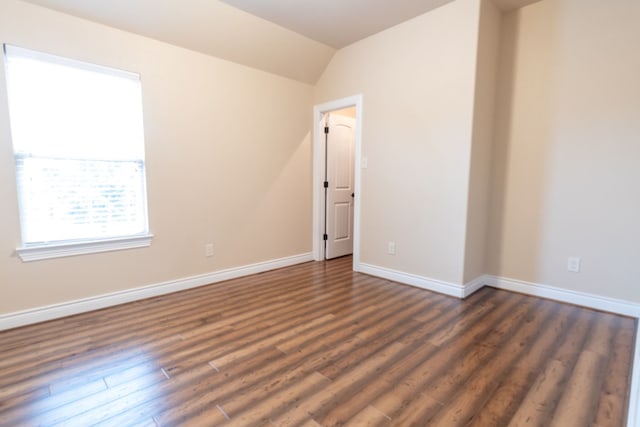 spare room featuring vaulted ceiling and dark wood-type flooring