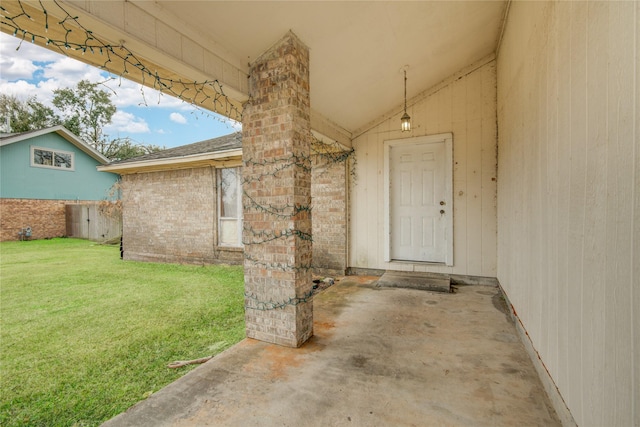 view of exterior entry featuring a lawn and a patio