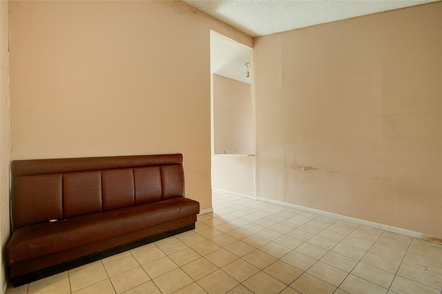 unfurnished room with a textured ceiling and light tile patterned floors