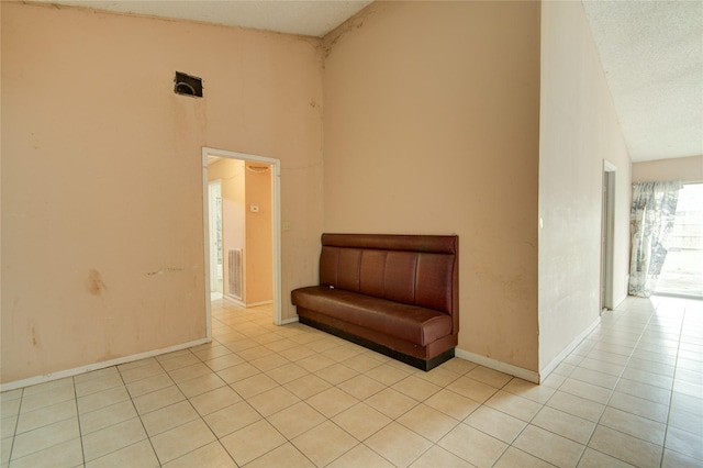 unfurnished room featuring high vaulted ceiling, a textured ceiling, and light tile patterned flooring