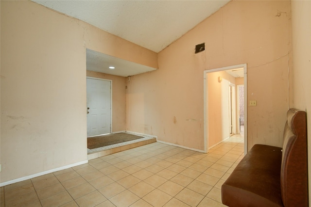 tiled spare room with vaulted ceiling and a textured ceiling