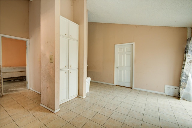 tiled empty room featuring high vaulted ceiling