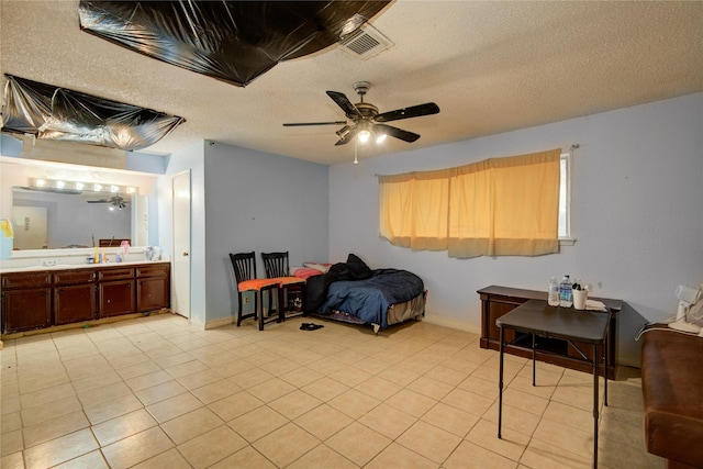 bedroom featuring ceiling fan, light tile patterned floors, a textured ceiling, and ensuite bath