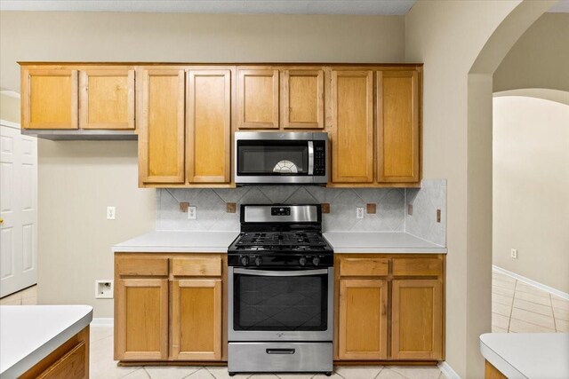 kitchen featuring light tile patterned floors, stainless steel appliances, light countertops, and decorative backsplash