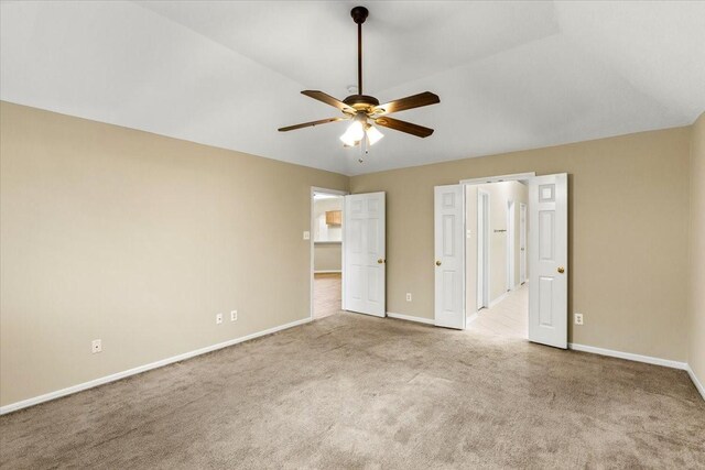 unfurnished bedroom featuring lofted ceiling, ceiling fan, baseboards, and light colored carpet