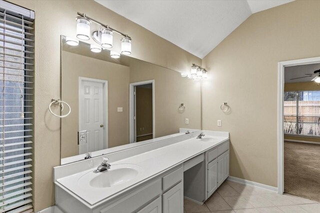 bathroom with tile patterned floors, vaulted ceiling, a sink, and double vanity