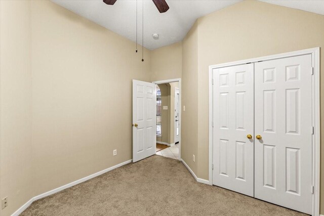 unfurnished bedroom with vaulted ceiling, baseboards, and light colored carpet