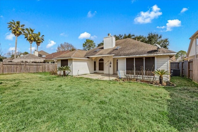 rear view of house with a yard, a chimney, a patio area, cooling unit, and a fenced backyard