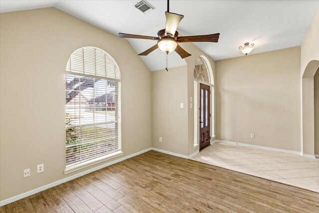 spare room featuring arched walkways, a wealth of natural light, light wood-style flooring, and visible vents