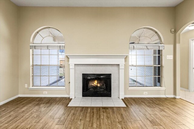 unfurnished living room featuring baseboards, a fireplace, and light wood-style floors