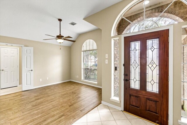 entrance foyer featuring lofted ceiling, a ceiling fan, baseboards, visible vents, and light wood-style floors