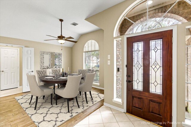 foyer featuring a ceiling fan, baseboards, vaulted ceiling, visible vents, and light wood-style floors