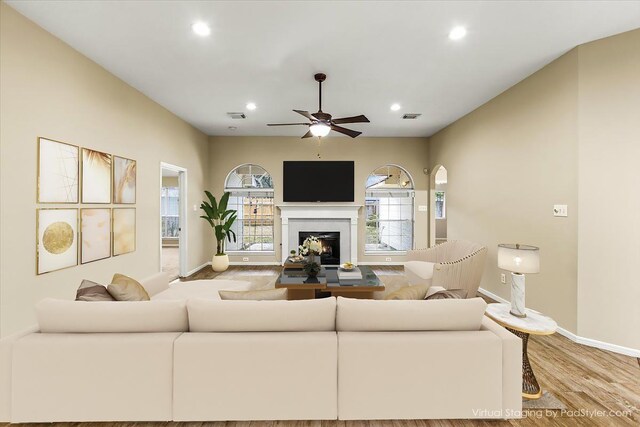 living room with a lit fireplace, light wood-type flooring, visible vents, and recessed lighting