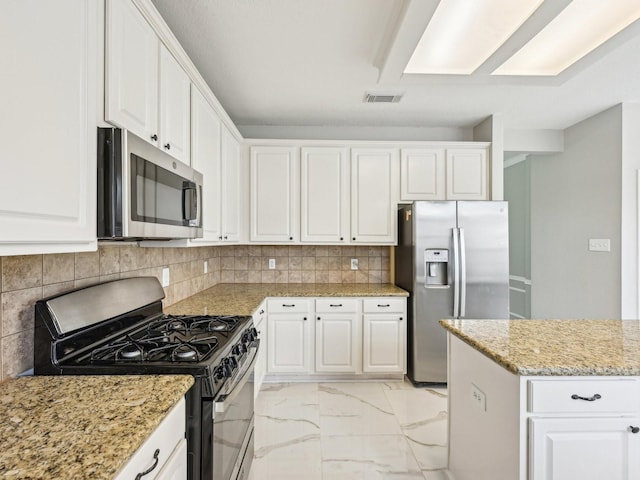 kitchen with white cabinetry, decorative backsplash, light stone countertops, and appliances with stainless steel finishes