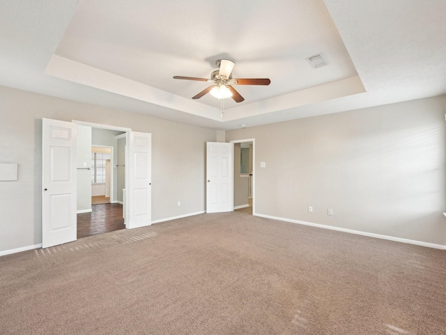 unfurnished bedroom featuring carpet flooring, ceiling fan, and a tray ceiling