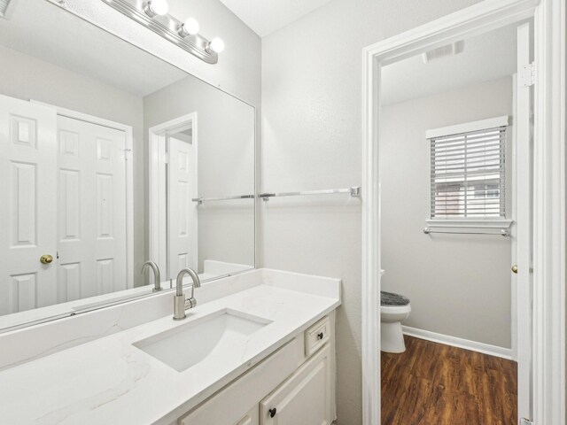 bathroom featuring wood-type flooring, vanity, and toilet