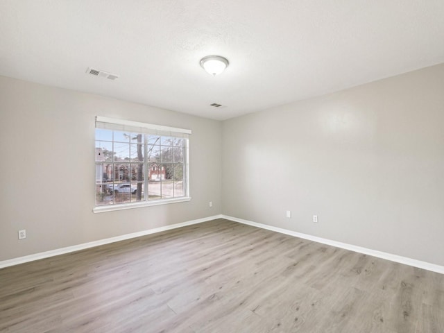 spare room with light hardwood / wood-style floors and a textured ceiling