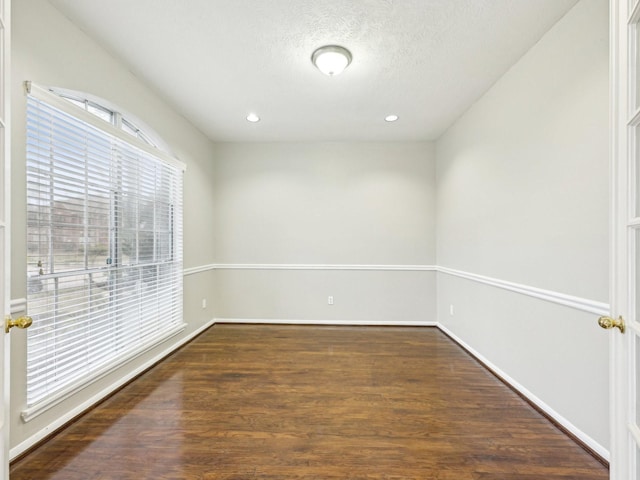 unfurnished room featuring a textured ceiling and dark hardwood / wood-style flooring