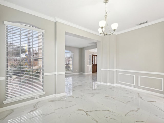 spare room with ornamental molding and a chandelier