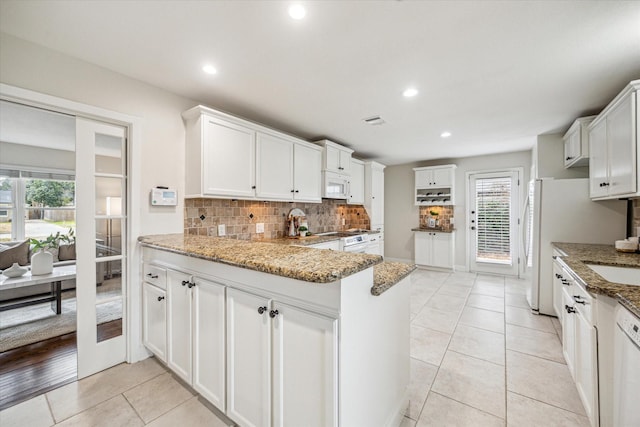 kitchen featuring decorative backsplash, kitchen peninsula, white cabinets, and stone countertops