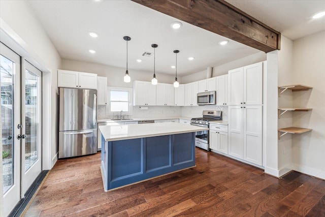 kitchen featuring stainless steel appliances, hanging light fixtures, a kitchen island, and white cabinets