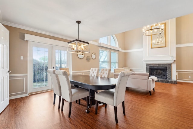 dining space featuring french doors, a chandelier, ornamental molding, a tile fireplace, and hardwood / wood-style flooring