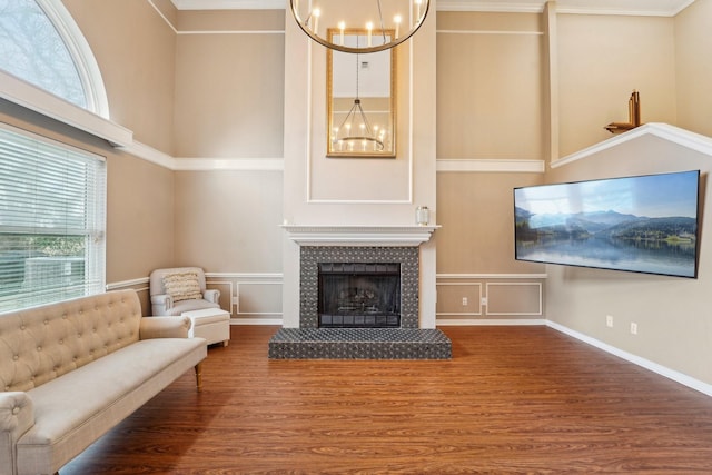 living room with a tiled fireplace, a notable chandelier, dark wood-type flooring, and a high ceiling