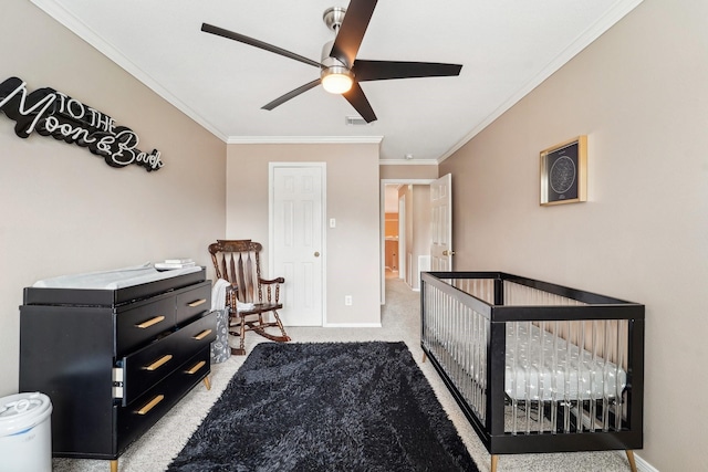 carpeted bedroom with a crib, ornamental molding, and ceiling fan