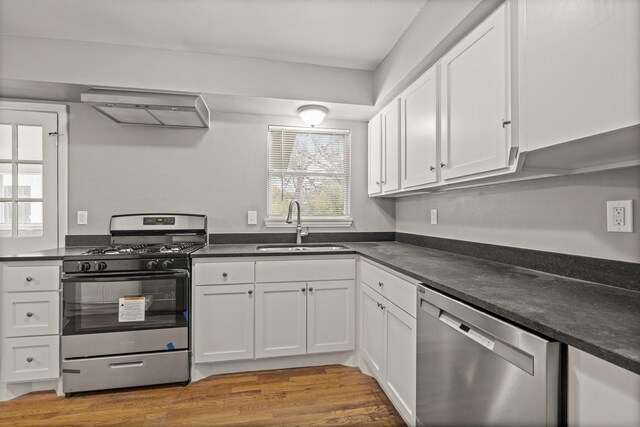 kitchen featuring sink, wall chimney range hood, stainless steel appliances, and white cabinets