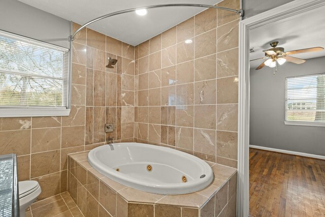 bathroom with tile walls, hardwood / wood-style floors, toilet, and ceiling fan