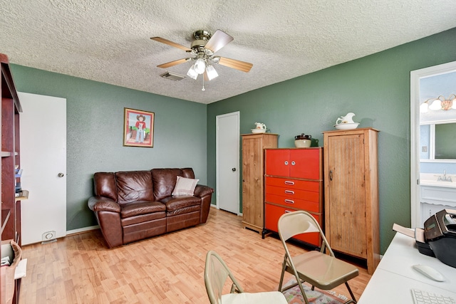 living room featuring a textured ceiling, light hardwood / wood-style floors, and ceiling fan