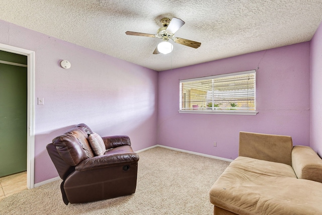 living area featuring ceiling fan, light colored carpet, and a textured ceiling