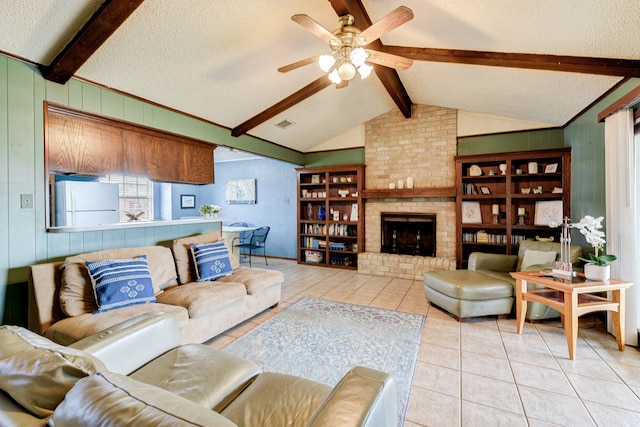 tiled living room with wood walls, vaulted ceiling with beams, a textured ceiling, ceiling fan, and a fireplace