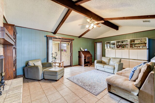 living room featuring light tile patterned flooring, ceiling fan, lofted ceiling with beams, and a textured ceiling