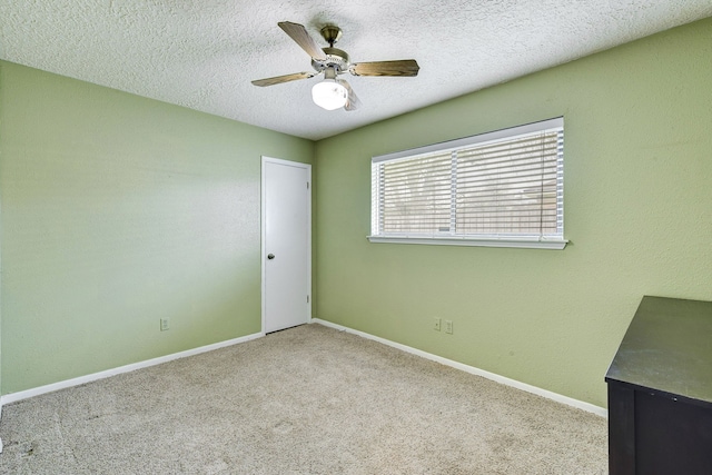 spare room with ceiling fan, light colored carpet, and a textured ceiling