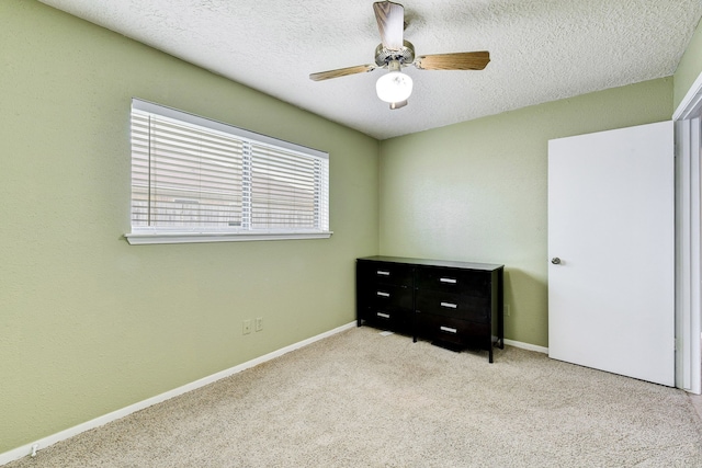 bedroom featuring ceiling fan, light colored carpet, and a textured ceiling