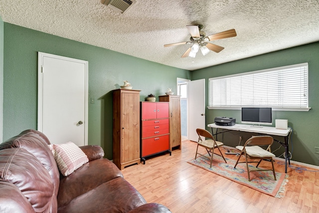 office with a textured ceiling, ceiling fan, and light hardwood / wood-style flooring